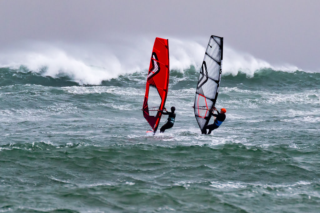 2 windsurfers approaching a wave at The Reef, Taranaki, New Zealand