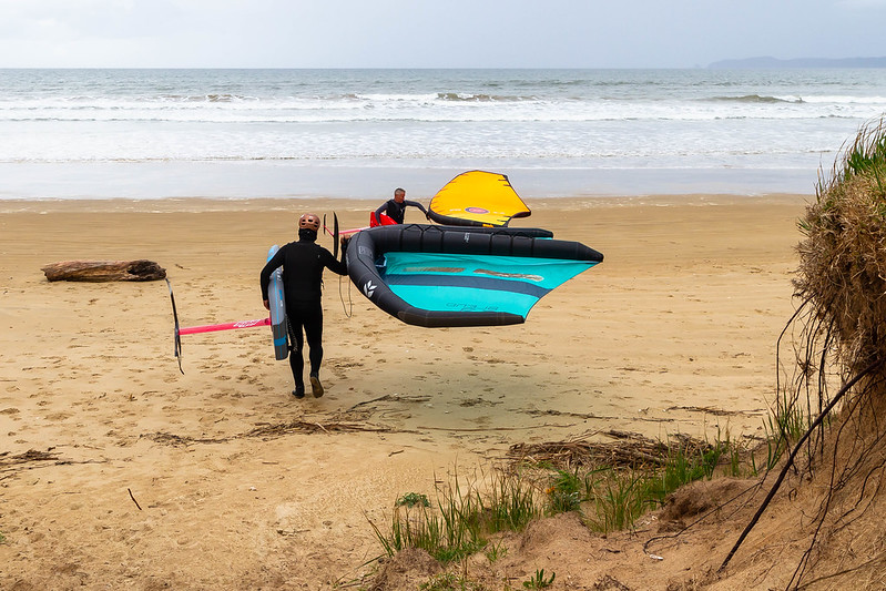 2 wingfoilers walking to the water in Tokerau Beach, Northland, New Zealand